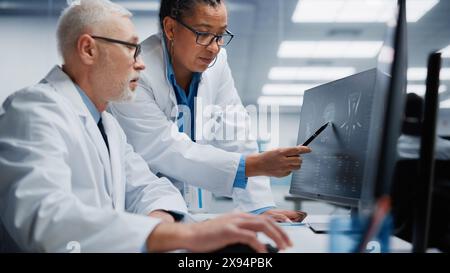 Medizinisches Krankenhaus: Neurologe und Neurochirurg sprechen, Computer verwenden, Patient MRT-Scan analysieren, Gehirn diagnostizieren. Health Clinic Lab: Zwei Fachärzte schauen sich CT-Scan an. Nahaufnahme Porträt Stockfoto