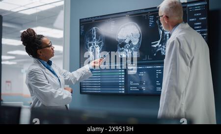 Medical Neuroscience Hospital Lab Meeting: Diverses Team von Neurochirurgen und Neurologen Analysieren TV-Bildschirm zeigt MRT-Scan mit Gehirnbildern, sprechen über Behandlungsmethode für kranke Patienten, neue Medikamente Heilung Stockfoto
