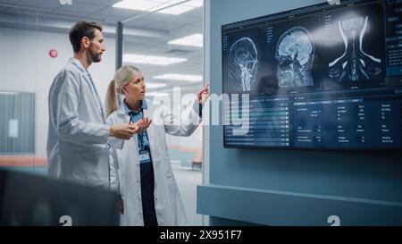 Medical Neuroscience Hospital Lab Meeting: Diverses Team von Neurochirurgen und Neurologen Analysieren TV-Bildschirm zeigt MRT-Scan mit Gehirnbildern, sprechen über Behandlungsmethode für kranke Patienten, neue Medikamente Heilung Stockfoto
