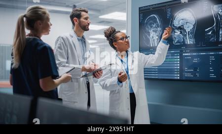 Medical Science Hospital Lab Meeting: Diverse Team von Neurologen, Neurowissenschaftlern, Neurochirurgen konsultieren TV Bildschirm zeigen MRT-Scan mit Gehirnbildern, sprechen über Behandlungsmethode, neue Medikamente Heilung Stockfoto