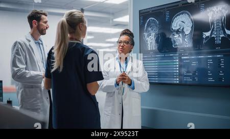 Medical Science Hospital Lab Meeting: Diverse Team von Neurologen, Neurowissenschaftlern, Neurochirurgen konsultieren TV Bildschirm zeigen MRT-Scan mit Gehirnbildern, sprechen über Behandlungsmethode, neue Medikamente Heilung Stockfoto