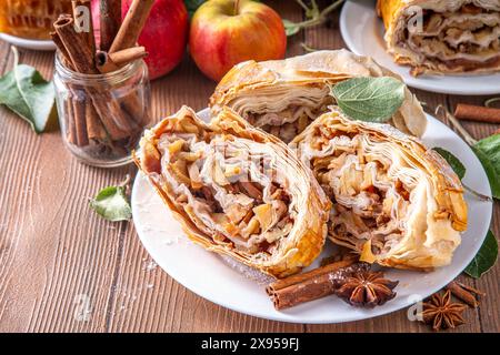 Hausgemachter herbstlicher Apfelstrudel mit karamelisierten Äpfeln, Rosinen, Nüssen, Honig, Zimtgewürzen, auf Teller auf Küchentisch Kopierraum Stockfoto