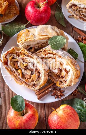 Hausgemachter herbstlicher Apfelstrudel mit karamelisierten Äpfeln, Rosinen, Nüssen, Honig, Zimtgewürzen, auf Teller auf Küchentisch Kopierraum Stockfoto