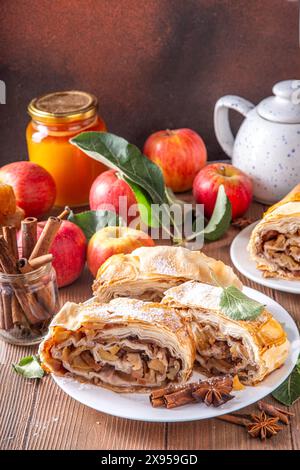 Hausgemachter herbstlicher Apfelstrudel mit karamelisierten Äpfeln, Rosinen, Nüssen, Honig, Zimtgewürzen, auf Teller auf Küchentisch Kopierraum Stockfoto