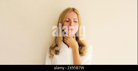 Porträt einer kranken erschöpften jungen Frau, die an akuten Schmerzen in der Rachengrippe leidet, berührt ihren Hals mit der Hand, sie fühlt sich schlecht Stockfoto