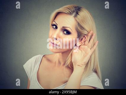 Die Frau hält ihre Hand nahe am Ohr und hört aufmerksam zu Stockfoto