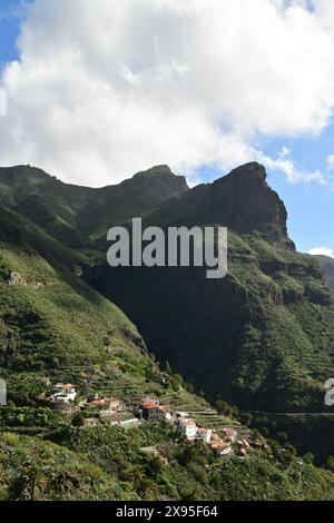 Charmantes Dorf am Hügel, eingebettet in üppige grüne Berge unter einem teilweise bewölkten Himmel, bietet eine malerische Aussicht Stockfoto