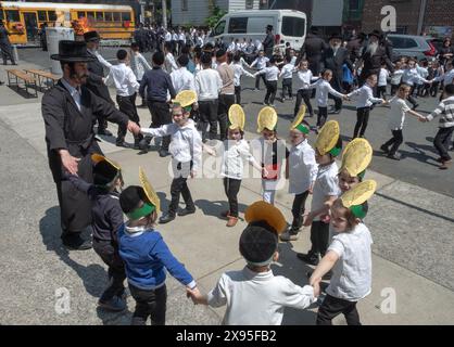 Während einer lag B'Omer-Feier tanzen Yeshiva-Jungs in Ferienhüten und ihre Rabbiner in der Nähe eines traditionellen Weihnachtsfeuers. In Brooklyn, NYC. Stockfoto