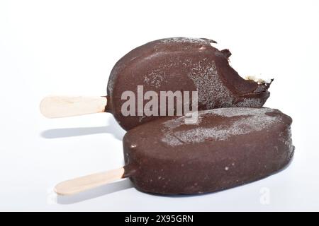 Nahaufnahme von zwei mit Schokolade überzogenen Eiscremes, einer wird gebissen. Stockfoto