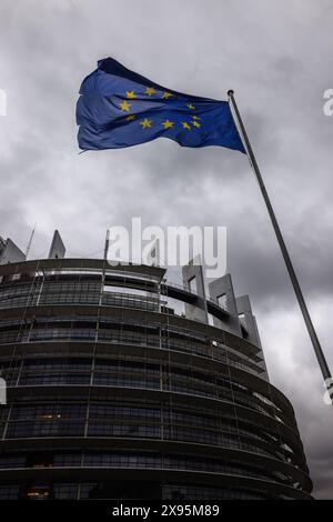 29. Mai 2024, Frankreich, Straßburg: Die Flagge der Europäischen Union fliegt im Wind vor dem Gebäude des Europäischen Parlaments. Beamte durchsuchen seit heute Morgen die Büros des Parlaments in Brüssel und Straßburg. Die Überfälle stehen offenbar im Zusammenhang mit der Affäre um das prorussische Nachrichtenportal "Voice of Europe", das angeblich im Zentrum einer russischen Einflussoperation steht. Die Europawahlen sind für den 9. Juni vorgesehen. Foto: Philipp von Ditfurth/dpa Stockfoto