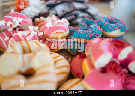 Nahaufnahme eines Tabletts mit Donuts in verschiedenen Farben und mit verschiedenen Arten von Streuseln. Buntes Dessert. Stockfoto