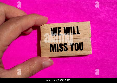 Wir werden Ihre Worte vermissen, die auf Holzblöcken mit rosa Hintergrund geschrieben sind. Konzeptionell werden wir dich vermissen Symbol. Kopierbereich. Stockfoto