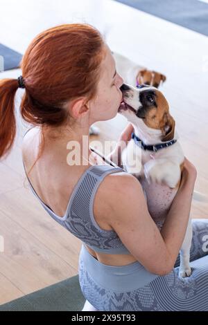 Glückliches Mädchen beim Yoga mit dem kleinen Jack Russell Terrier Welpen. Gesunder Lebensstil und Meditation Stockfoto