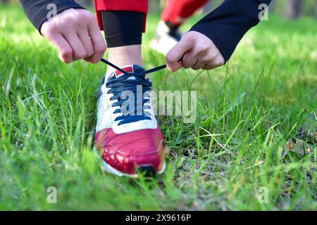 Eine Frau bindet die Schnürsenkel an ihre Turnschuhe im Park Stockfoto