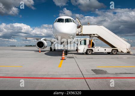 Weißes Passagierflugzeug mit Luftreppen auf dem Flughafenvorfeld Stockfoto