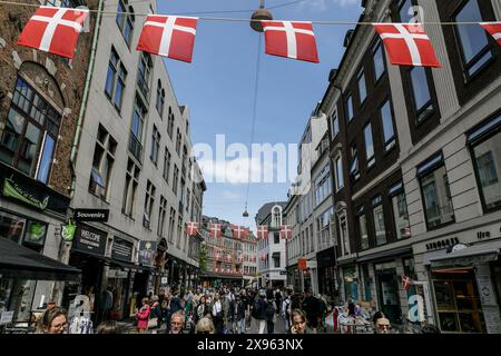 Kopenhagen, Dänemark. Mai 2024. Die Menschen laufen auf einer Straße im Zentrum von Kopenhagen, über der dänische Fahnen hängen. Kopenhagen belegt bei der Mercer Quality of Living Survey 2023 weltweit den vierten Platz. Eine stabile Wirtschaft, ausgezeichnete Bildungsangebote und hohe soziale Sicherheit machen es für Einheimische und Touristen attraktiv. Kopenhagen ist auch eine der teuersten Städte der Welt und ein beliebtes Touristenziel. Quelle: SOPA Images Limited/Alamy Live News Stockfoto