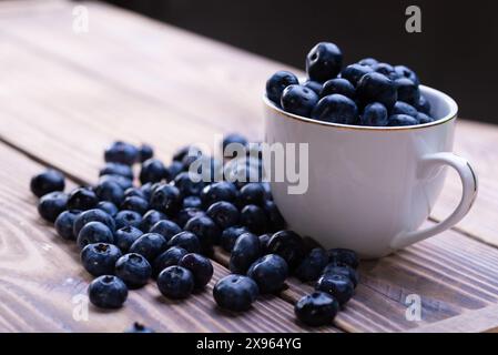Frische Heidelbeeren in einer weißen Tasse auf einem Holztisch Stockfoto