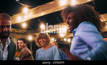 Nahaufnahme von schönen sorglosen Freunden tanzen zusammen und feiern ein Abendfest bei einer Party . Verschiedene multiethnische junge Erwachsene haben Spaß bei einer Firmenfeier in einem Restaurant. Stockfoto