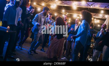 Schöne unbeschwerte Freunde tanzen zusammen und feiern ein Abendfest bei einer Party . Verschiedene multiethnische junge Erwachsene haben Spaß bei einer Firmenfeier in einem Restaurant. Stockfoto