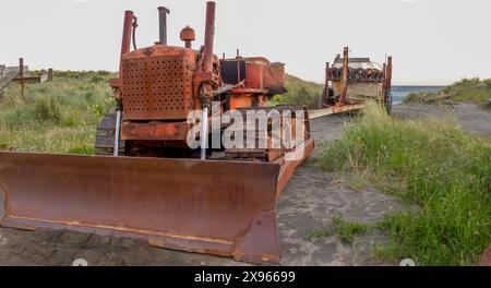 Alter Bulldozer und Boot auf Anhänger am Strand in Wairarapa, Neuseeland. Stockfoto