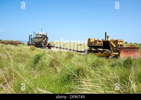 Alte Bulldozer schleppten früher Boote zum Wasser und zurück in die Dünen an der Wairarapa-Küste bei Tora. Stockfoto