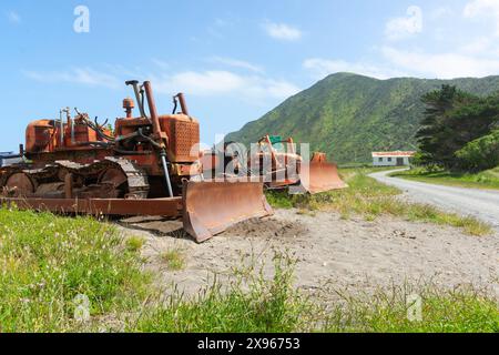 Alte Bulldozer schleppten früher Boote zum Wasser und zurück in die Dünen an der Wairarapa-Küste bei Tora. Stockfoto