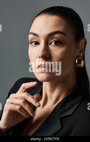 Elegante Frau in einem schwarzen Hemd, die selbstbewusst für ein Foto posiert. Stockfoto