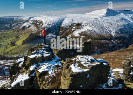 Walker blickt über Grindslow Knoll und das Edale Valley von der Felsformation Ringing Roger im Winter, Kinder Scout, Peak District National Park, der Stockfoto