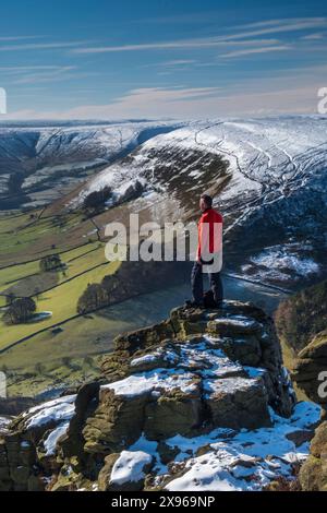 Walker blickt über das Edale Valley von der Felsformation Ringing Roger im Winter, Kinder Scout, Peak District National Park, Derbyshire, England, UN Stockfoto