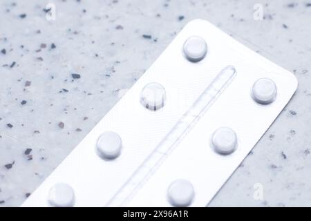Eine rechteckige Blisterpackung Pillen mit einem Kreismuster in Elektroblau auf einer Plastikhülle. Es sitzt auf einer Metallplatte, ähnlich einem Moden Stockfoto