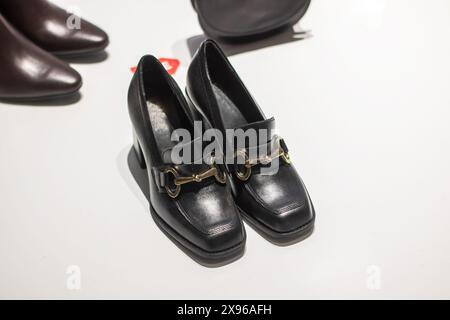 Es gibt ein Paar elegante schwarze Schuhe mit einer stilvollen goldenen Schnalle an der Seite, perfekt für jeden formellen Anlass oder einen Abend Stockfoto