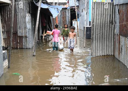 Slum Children waten durch einen überfluteten Innenhof, nachdem der Zyklon Remal am 29. Mai 2024 im Balumath Slum in Dhaka, Bangladesch, gelandet war Stockfoto