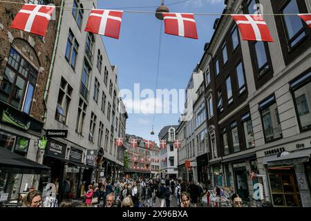 Kopenhagen, Dänemark. Mai 2024. Die Menschen laufen auf einer Straße im Zentrum von Kopenhagen, über der dänische Fahnen hängen. Kopenhagen belegt bei der Mercer Quality of Living Survey 2023 weltweit den vierten Platz. Eine stabile Wirtschaft, ausgezeichnete Bildungsangebote und hohe soziale Sicherheit machen es für Einheimische und Touristen attraktiv. Kopenhagen ist auch eine der teuersten Städte der Welt und ein beliebtes Touristenziel. (Credit Image: © Volha Shukaila/SOPA Images via ZUMA Press Wire) NUR REDAKTIONELLE VERWENDUNG! Nicht für kommerzielle ZWECKE! Stockfoto