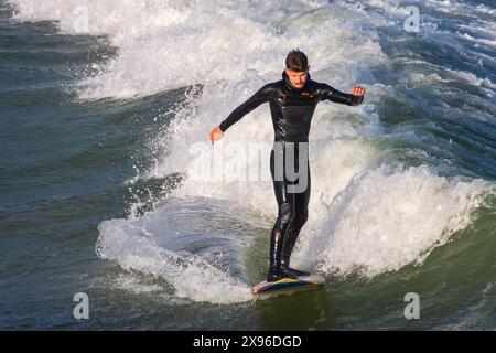 East Cliff Beach, Bournemouth - 14. Mai 2024: Männlicher Surfer auf einem Surfbrett auf einer Welle. Stockfoto