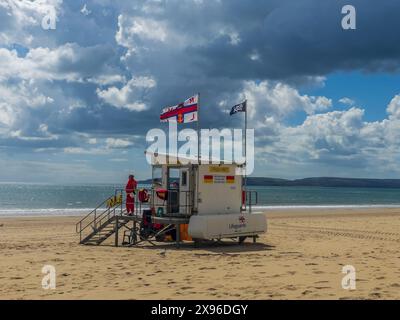 West Cliff Beach, Bournemouth, Großbritannien - 12. April 2024: Flaggen winken im Wind auf einem RNLI-Wachturm am Sandstrand. Stockfoto