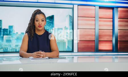 TV Studio Live News Programm: Schwarze weibliche Moderatorin berichtet über Wirtschaft, Wirtschaft, Unterhaltung. Tv-Kabelkanal Anchor Talks. Network Broadcast Newsroom Studio TV Show Konzept Stockfoto