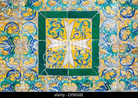 Ein farbenfrohes Kreuzdesign auf alten glasierten Keramikfliesen, ausgestellt im Museum der Schönen Künste in Sevilla, Spanien. Stockfoto