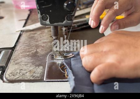 Frauenhände Nähstoffreparaturen an Nähmaschinen im Nähprozess. Stockfoto