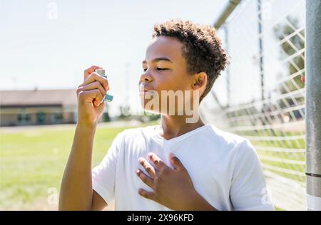 Das Kind verwendet im Park einen Asthma-Inhalator Stockfoto