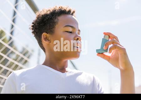 Das Kind verwendet im Park einen Asthma-Inhalator Stockfoto