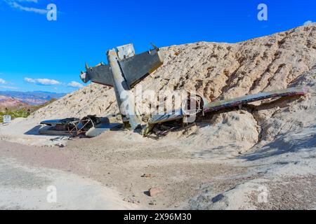 Nelson, Nevada - 15. April 2024: Nahaufnahme eines abgestürzten Flugzeugs, das teilweise in sandigem Gelände mit einem klaren blauen Himmel im Hintergrund begraben ist Stockfoto