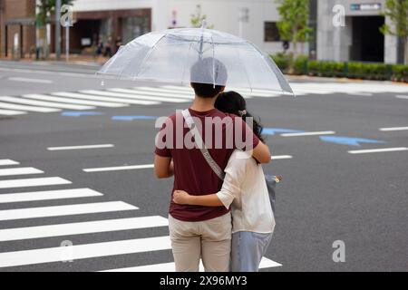 Tokio, Japan. Mai 2024. Ein paar Umarmungen unter einem Schirm an einer Kreuzung. (Foto: Stanislav Kogiku/SOPA Images/SIPA USA) Credit: SIPA USA/Alamy Live News Stockfoto