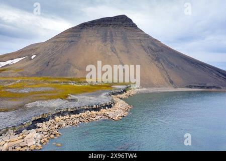 Blick aus der Vogelperspektive über Felsformationen und Küstenerosion entlang der felsigen Küste von Boltodden im Sommer, Kvalvågen, Svalbard / Spitzbergen, Norwegen Stockfoto