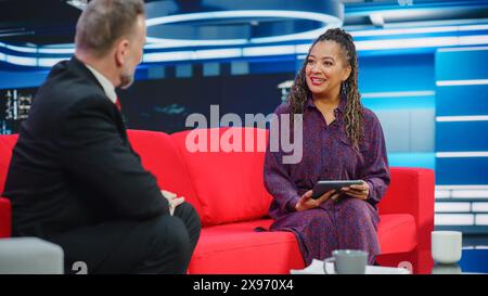 Talk Show TV-Programm, News Interview und Diskussion: Moderator und Gastgespräch. Kabelkanal-Hosts Führen Eine Freundliche Unterhaltung. TV-Studio und Newsroom Entertainment-Konzept Stockfoto