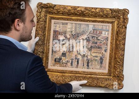 London, Großbritannien. 29. Mai 2024. Ein Mitarbeiter hängt „La Place du Havre, Effet de Pluie“, 1897, von Camille Pissarro bei einer Vorschau von „Celebrating 150 Years of Impressionism“, einer Ausstellung impressionistischer und postimpressionistischer Werke in der Galerie Stern Pissarro in St. James Die erste impressionistische Ausstellung 1874, organisiert von Pissarro, Monet, Degas, Renoir, und Sisley brachte Werke von 31 Künstlern zusammen, die dafür bekannt waren, Landschaften und zeitgenössisches Leben en plein Air (außerhalb) zu malen, anstatt starre akademische Malerei. Die Show läuft vom 30. Mai bis zum 29. Juni 2024. Quelle: Stephen Chung Stockfoto