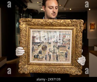 London, Großbritannien. 29. Mai 2024. Ein Mitarbeiter präsentiert „La Place du Havre, Effet de Pluie“, 1897, von Camille Pissarro bei einer Vorschau auf „Celebrating 150 Years of Impressionism“, eine Ausstellung impressionistischer und postimpressionistischer Werke in der Galerie Stern Pissarro in St. James Die erste impressionistische Ausstellung 1874, organisiert von Pissarro, Monet, Degas, Renoir, und Sisley brachte Werke von 31 Künstlern zusammen, die dafür bekannt waren, Landschaften und zeitgenössisches Leben en plein Air (außerhalb) zu malen, anstatt starre akademische Malerei. Die Show läuft vom 30. Mai bis zum 29. Juni 2024. Quelle: Stephen Chu Stockfoto