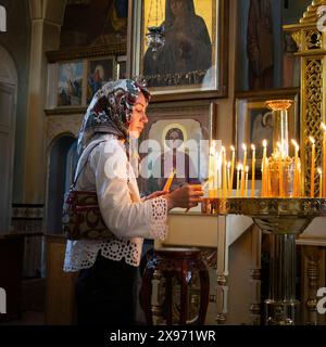 Tel Aviv, Israel - 6. April 2024: Eine Frau zündet Kerzen in der Russisch-orthodoxen Kirche St. Peter und St. Tabitha in Tel Aviv an. Stockfoto