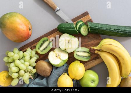 Frisches Obst, Trauben, Zitronen, Gurken, Bananen, Mangos, kiwi und Äpfel auf einem Schneidebrett. Stockfoto