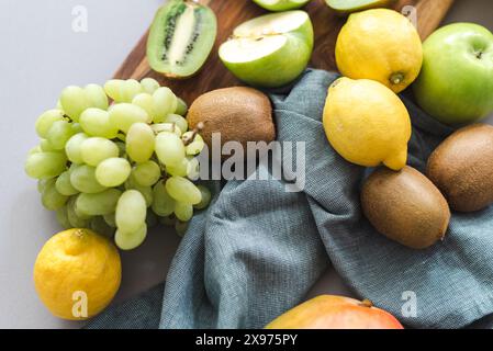 Frisches Obst, Trauben, Zitronen, Bananen, Mangos, Kiwi, und Äpfel auf einem Schneidebrett. Stockfoto