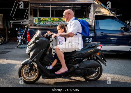 Ein Vater holt seine Tochter von der Schule ab und fährt mit einem Roller in Pattaya Thailand nach Hause. Fahrt entlang Soi Buakhao im Zentrum von Pattaya. Stockfoto